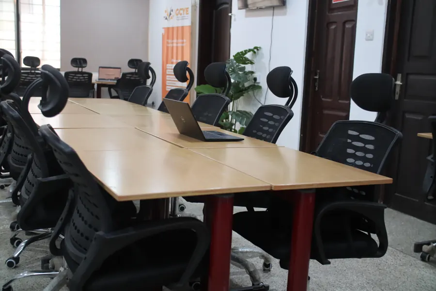 Shared worktable with a laptop, seating and greenery at yecSpace